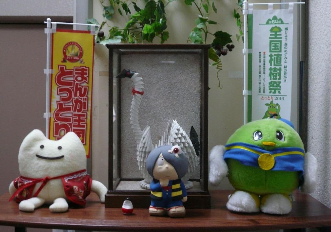 A shelf with three plush toys, a framed picture, and two banners.