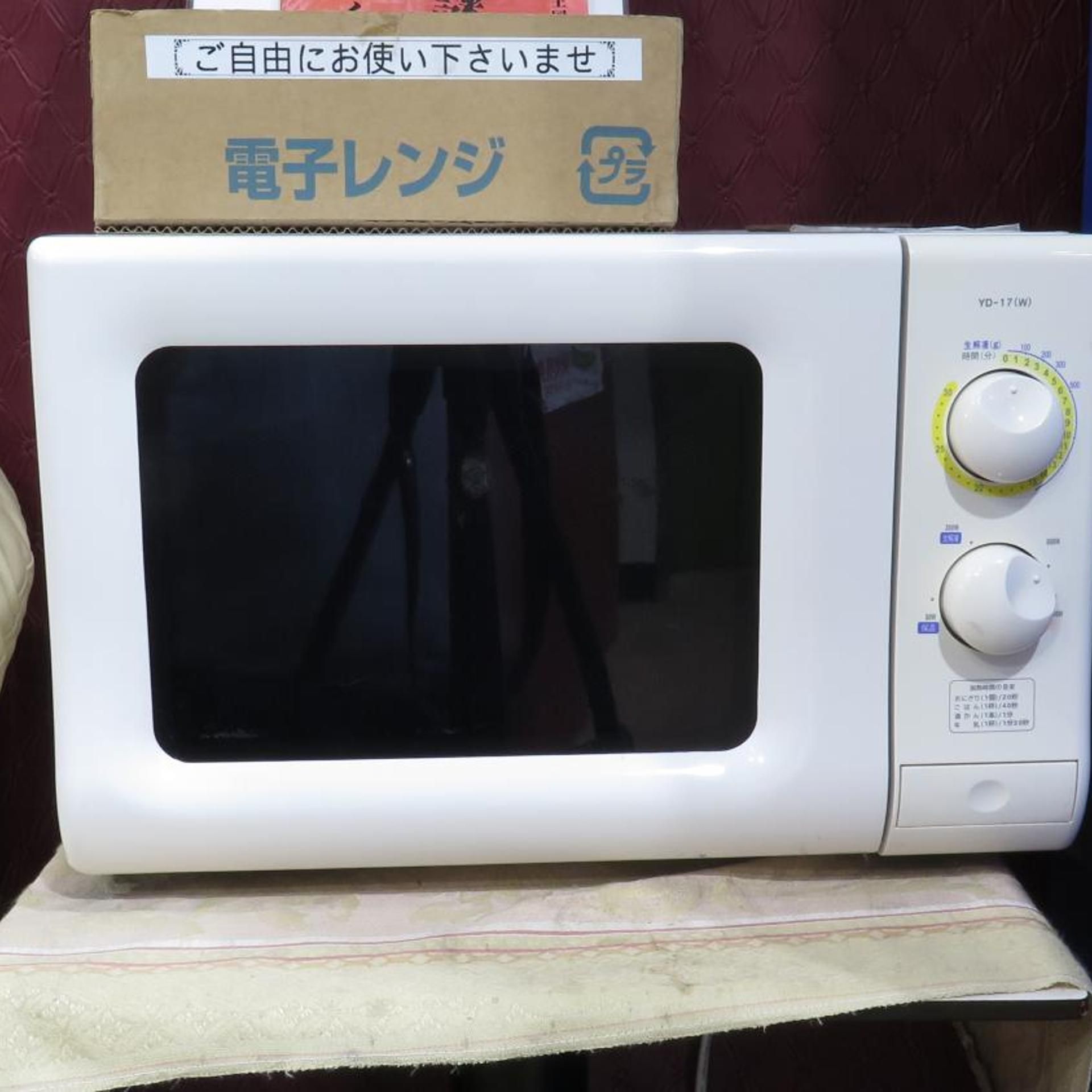 A white microwave oven with a digital display and control knobs on the right side, placed on a table with a patterned tablecloth.