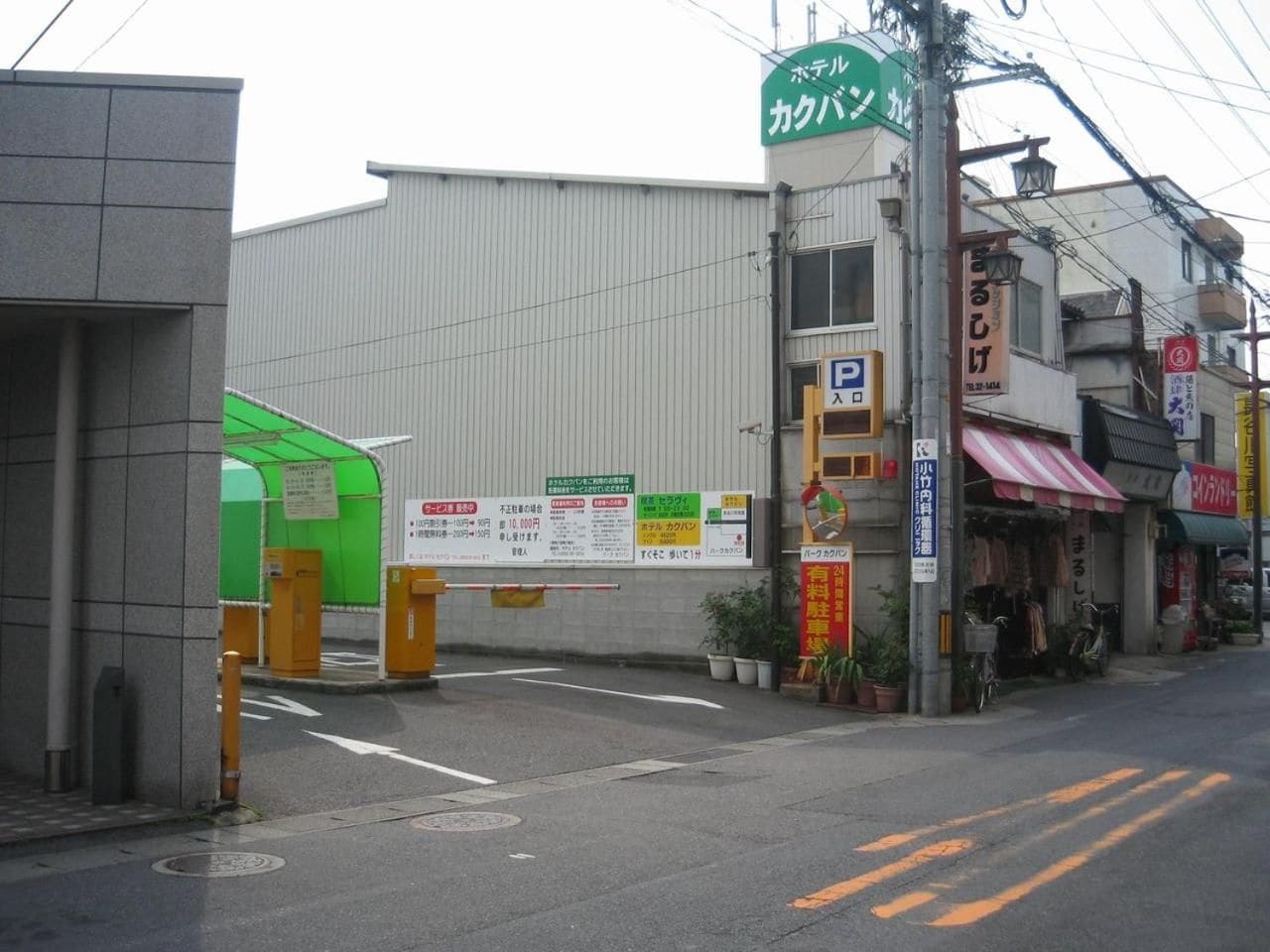 A street with a building that has a green awning and a sign with Japanese text.