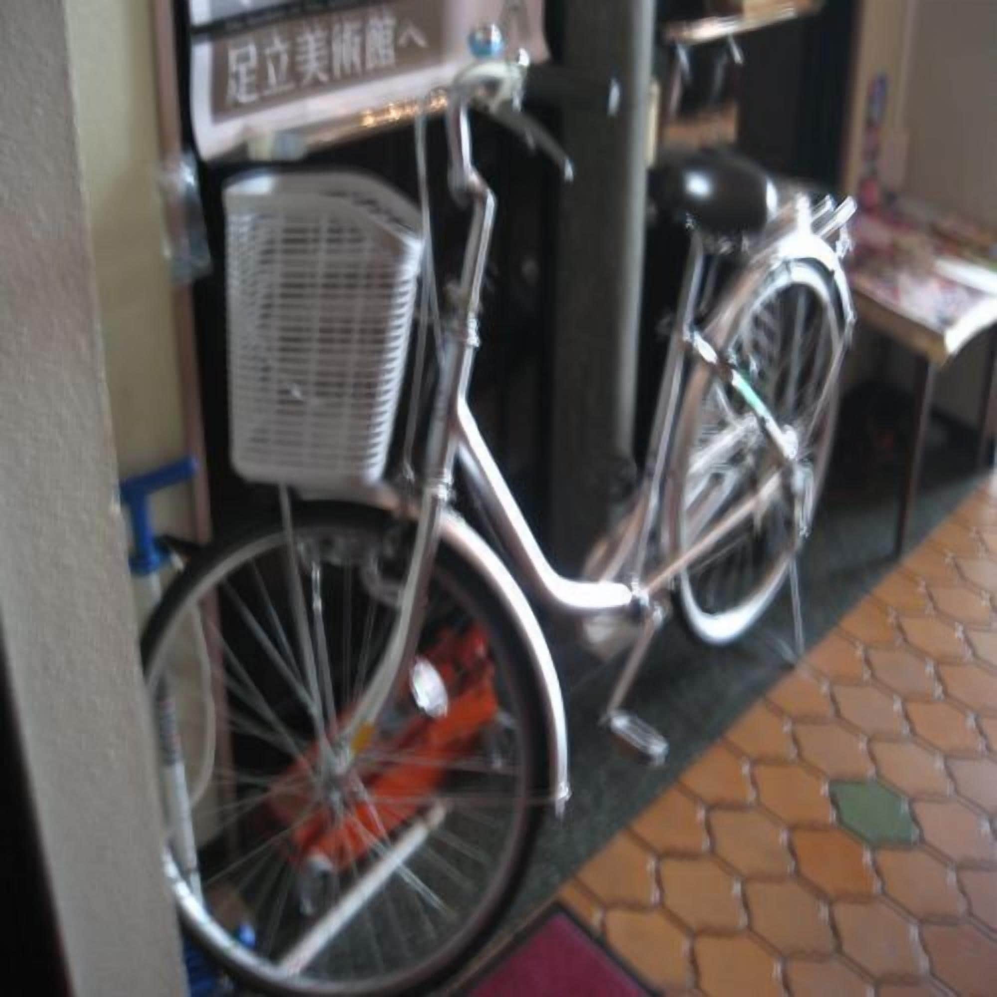 A bicycle with a basket, a wall-mounted sign, and a tiled floor.