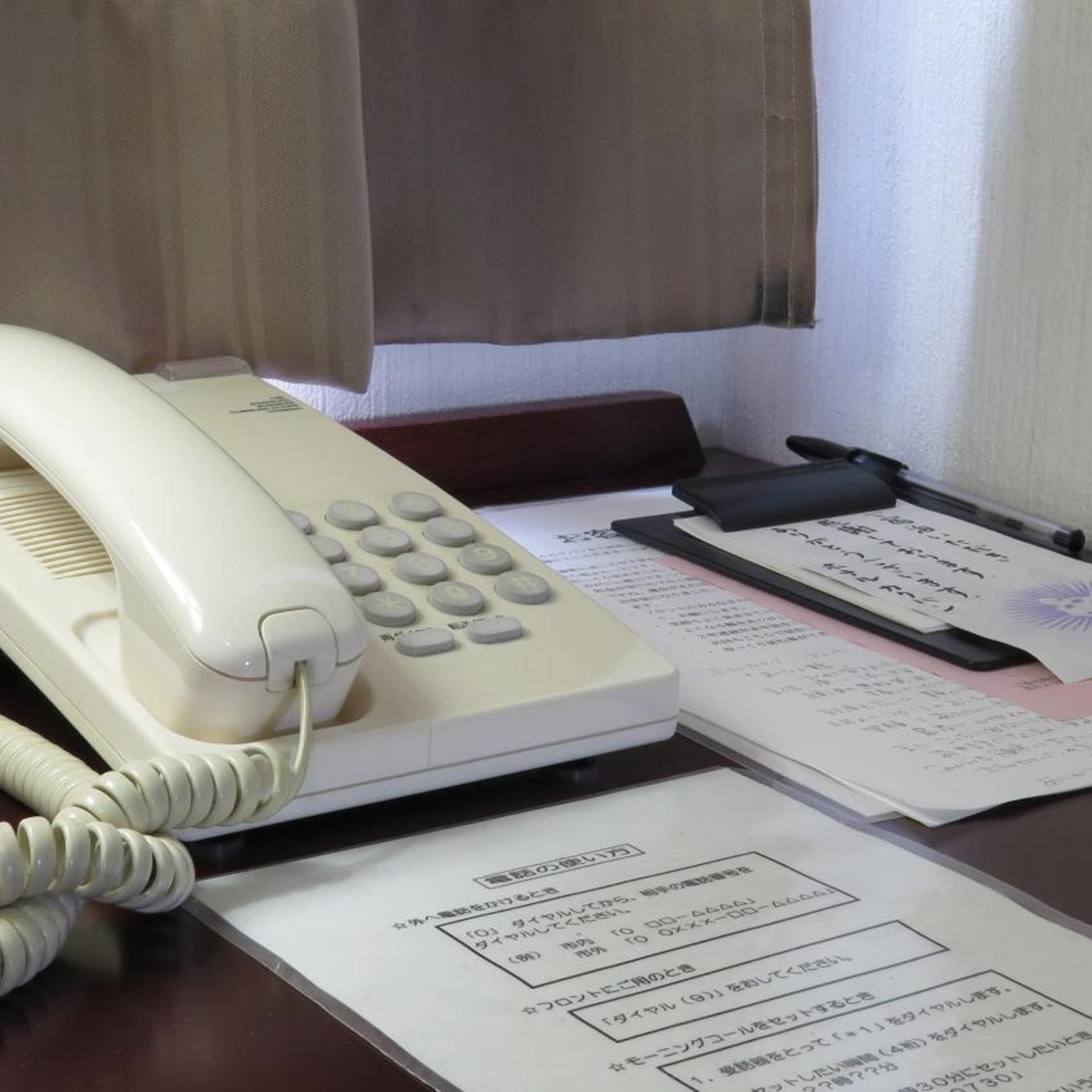 Un escritorio con un teléfono blanco, papeles y una pluma negra.