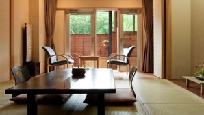 Perinteinen japanilaistyylinen huone, jossa on tatamimatto, matala pöytä tyynyineen ja liukuovi, joka johtaa ulkotilaan.