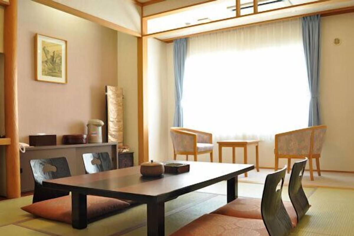 A traditional Japanese room with tatami flooring, a low table, and chairs.