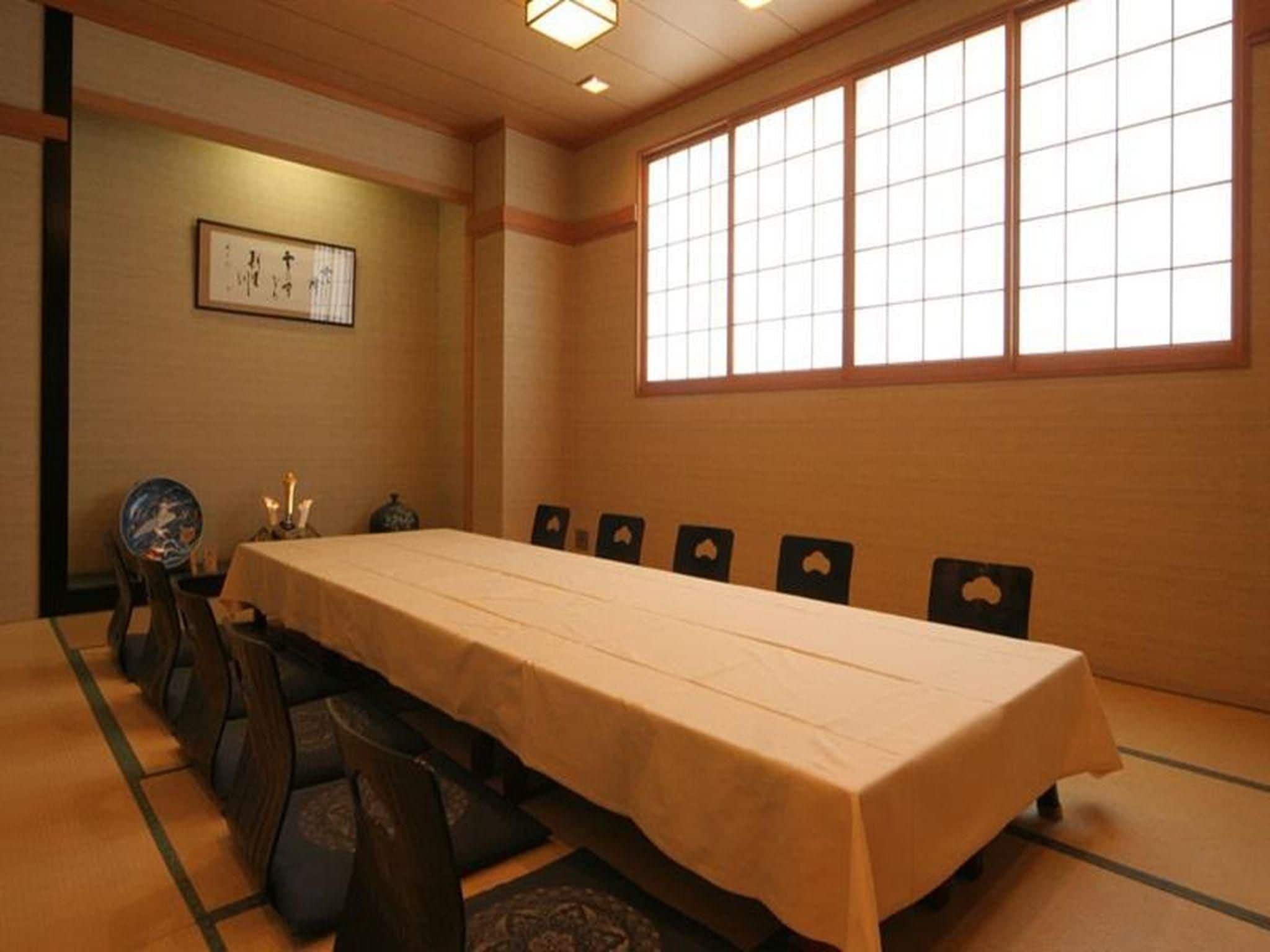 A traditional Japanese meeting room with tatami flooring, a long table, and shoji screens.