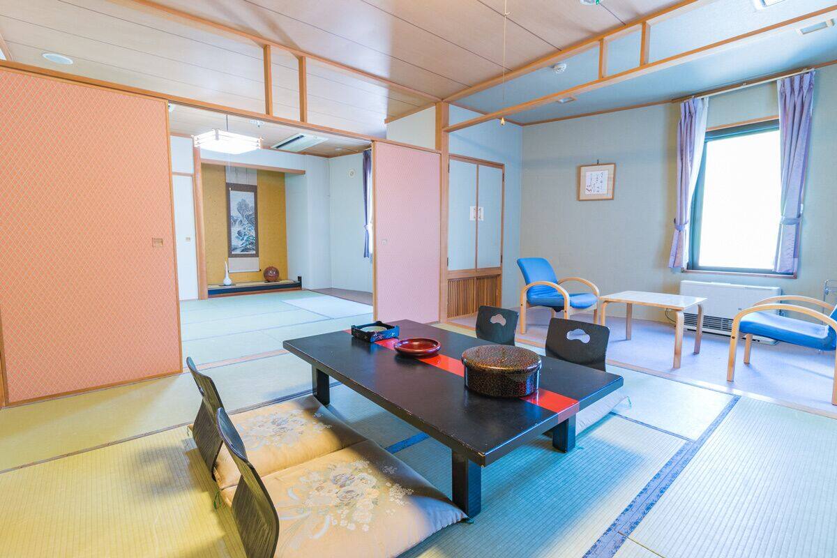 A traditional Japanese room with tatami flooring, a low table with cushions, and a sliding door.