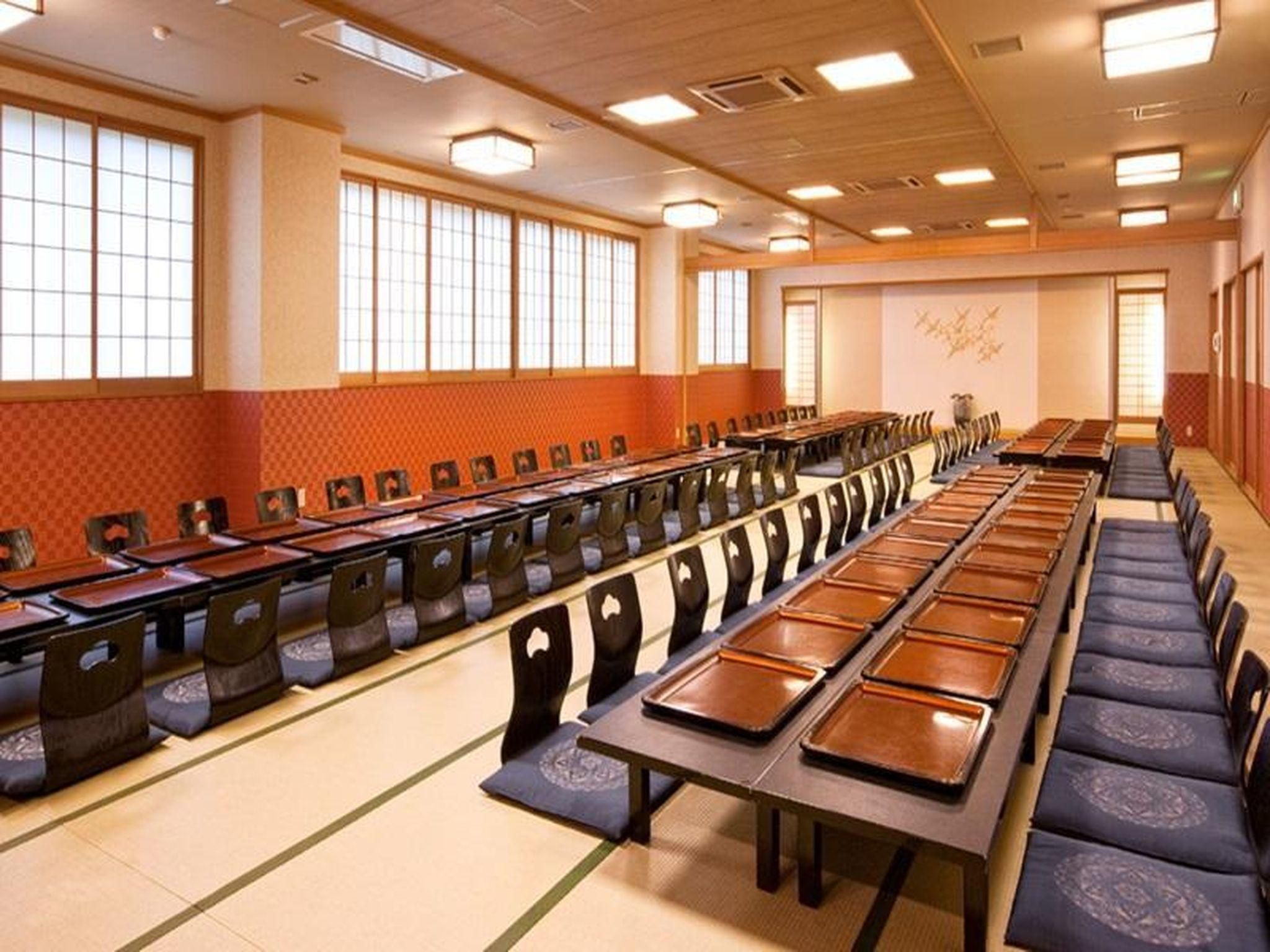A conference room with long tables and chairs, large windows, and a tiled floor.