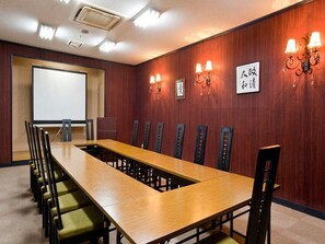 A conference room with a long table, chairs, a projector screen, and wall-mounted lighting. - Otaru Asarigawa Onsen Musashitei (Otaru)