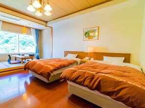 Habitación de hotel con dos camas, un escritorio y un ventanal con cortinas.