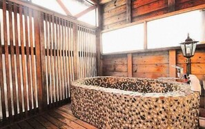 A stone hot tub in a wooden room with a slatted wall and a lamp. - Otaru Asarigawa Onsen Musashitei (Otaru)