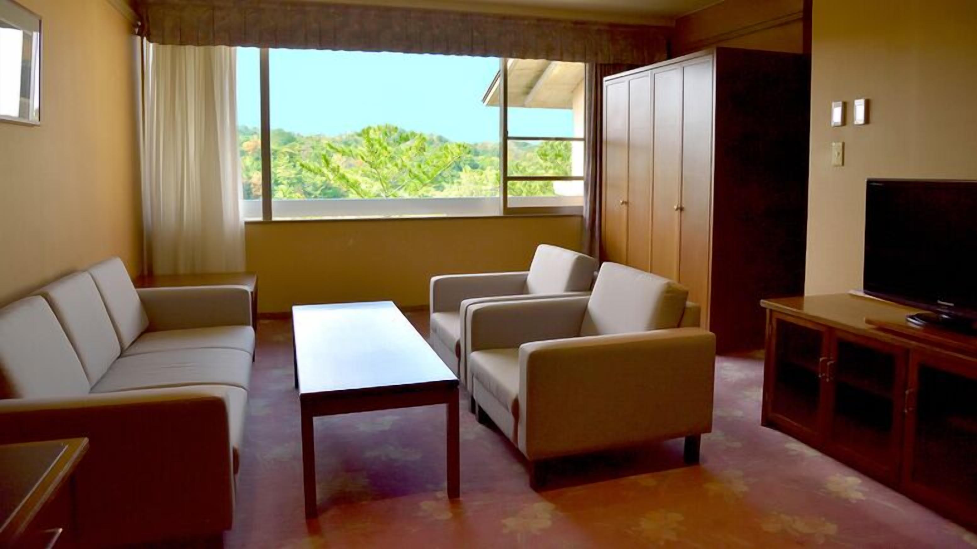 A living room with a sofa, armchairs, a coffee table, a TV, and a wardrobe.
