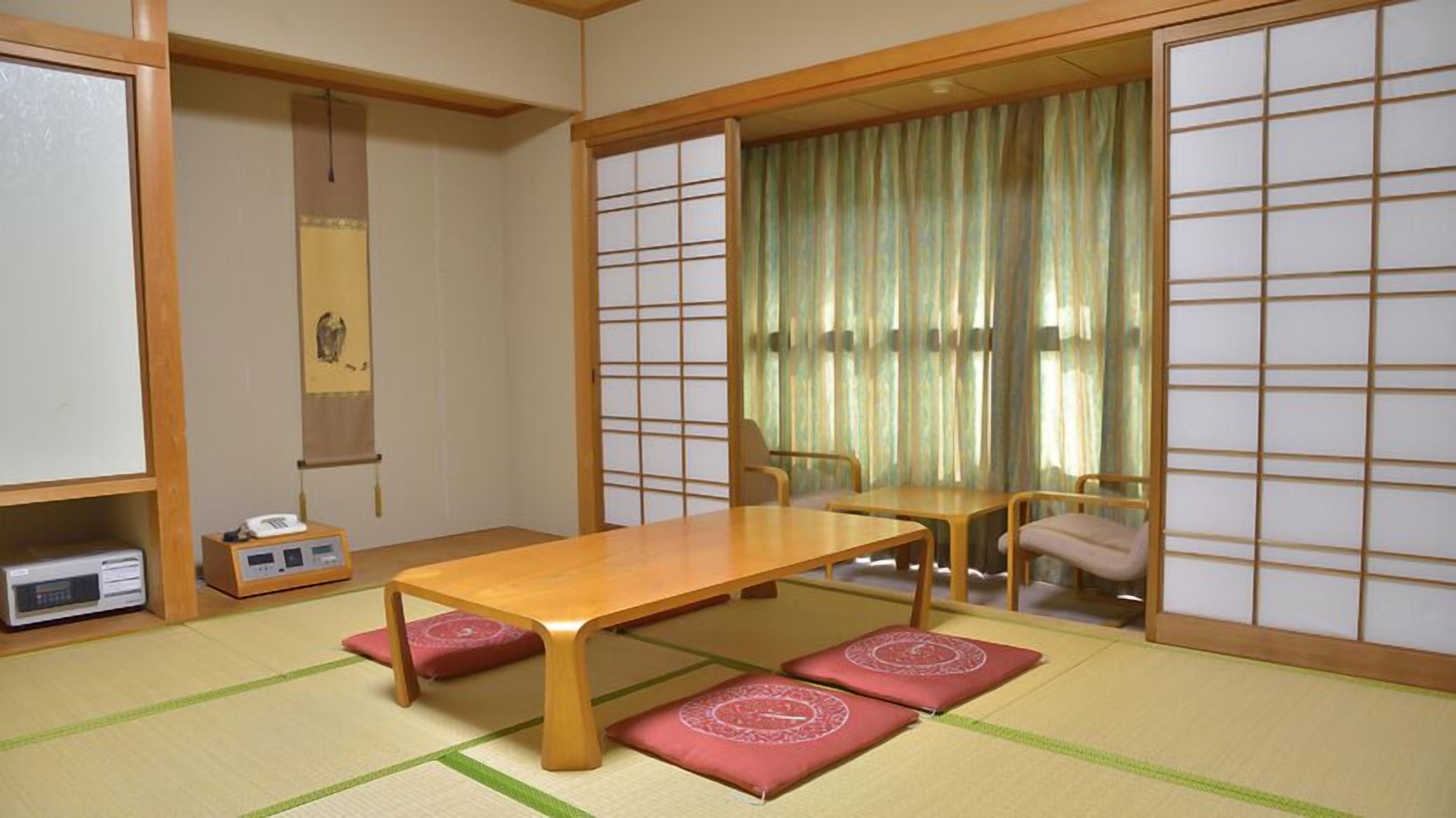 A traditional Japanese room with tatami flooring, a low table, and sliding doors.