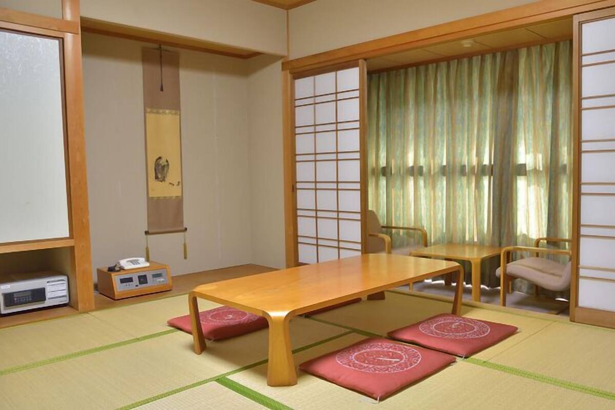 A traditional Japanese room with tatami flooring, a low table, and sliding doors.