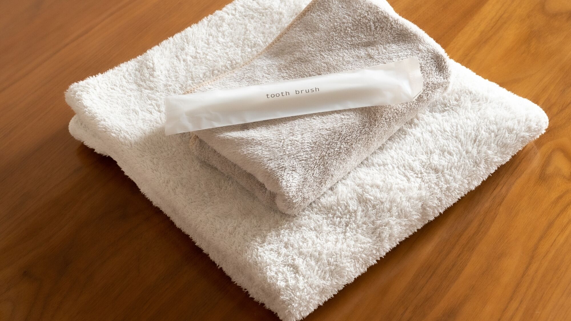 A white towel with a tooth brush on a wooden surface.