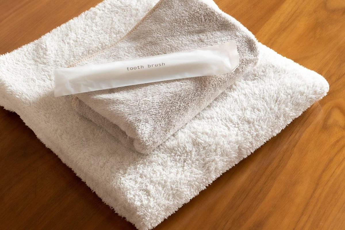 A white towel with a tooth brush on a wooden surface.