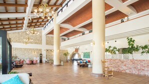 A spacious lobby with high ceilings, exposed brick walls, and a central seating area with a sofa and chairs.