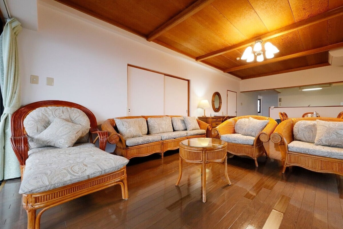 Una habitación con techo de madera, un conjunto de sofá, una mesa redonda y un espejo en la pared.