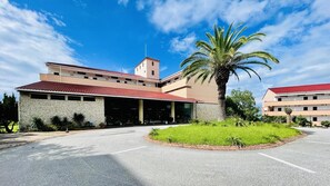 A hotel with a stone facade, a red-tiled roof, and a palm tree in the foreground. - Resort Hotel Umibe no Kajuen (Konan)