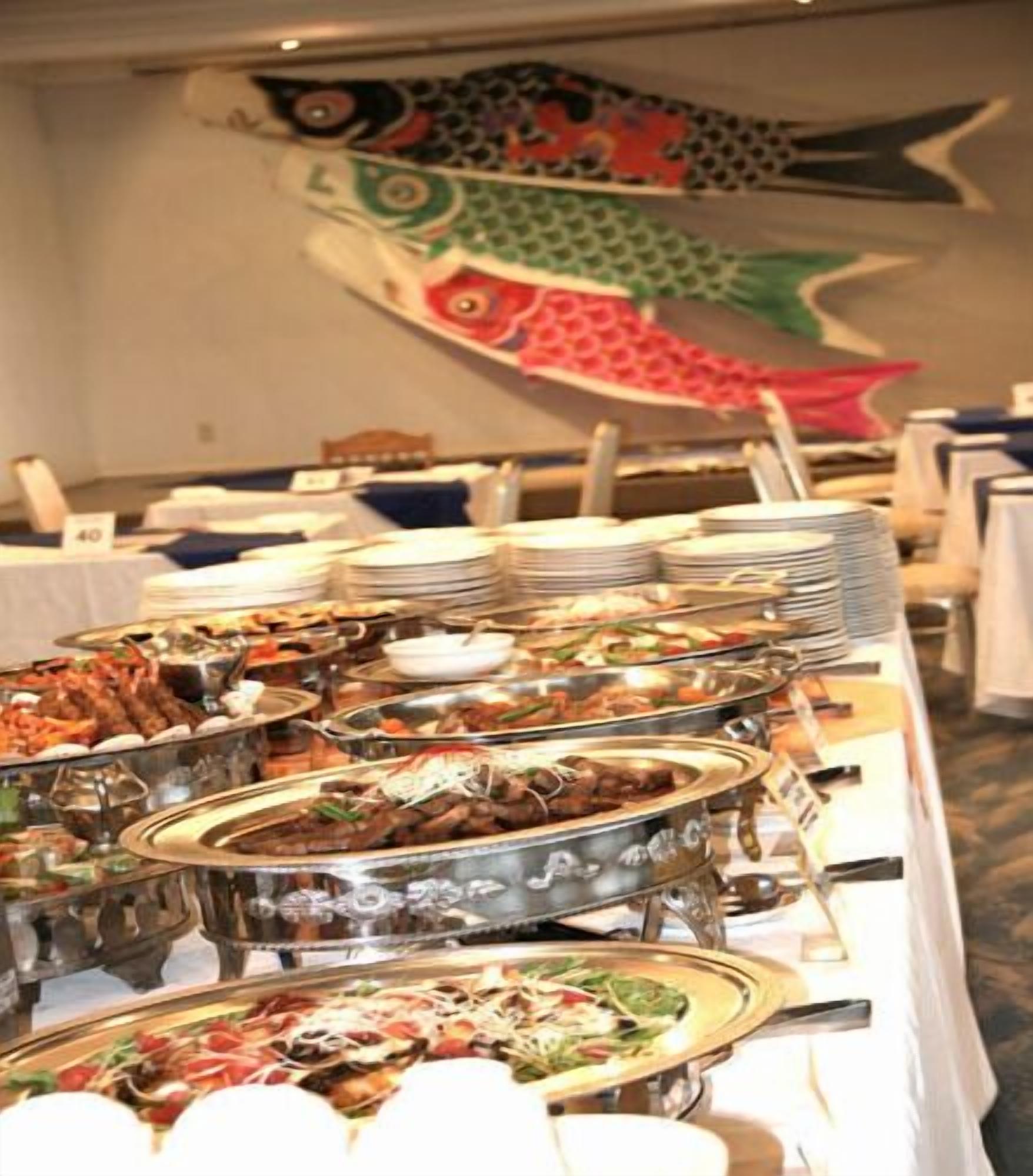 A buffet with various dishes and a large fish mural on the wall.