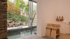 Un espacio de spa con una pared de piedra, un pequeño elemento acuático y taburetes de madera.