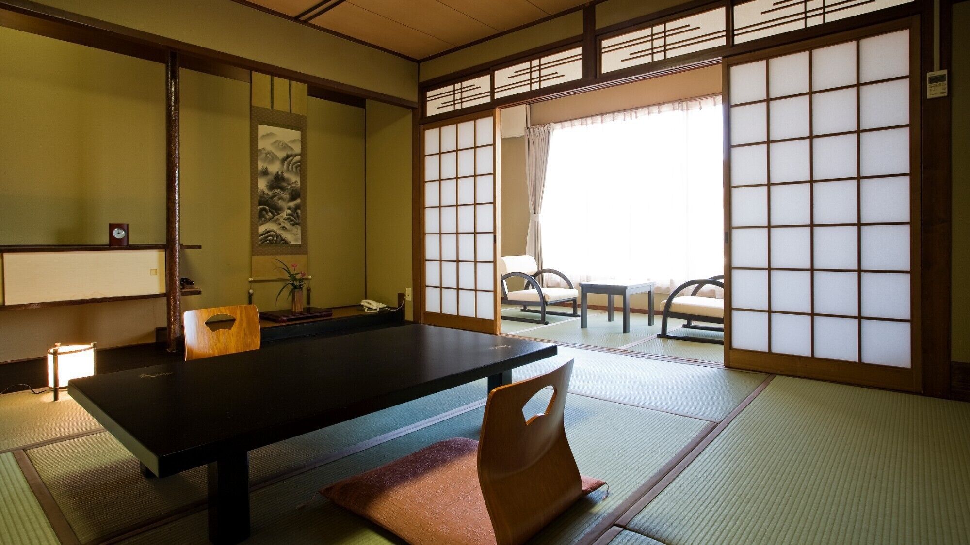 A traditional Japanese room with tatami flooring, a low table, a chair, and sliding doors.