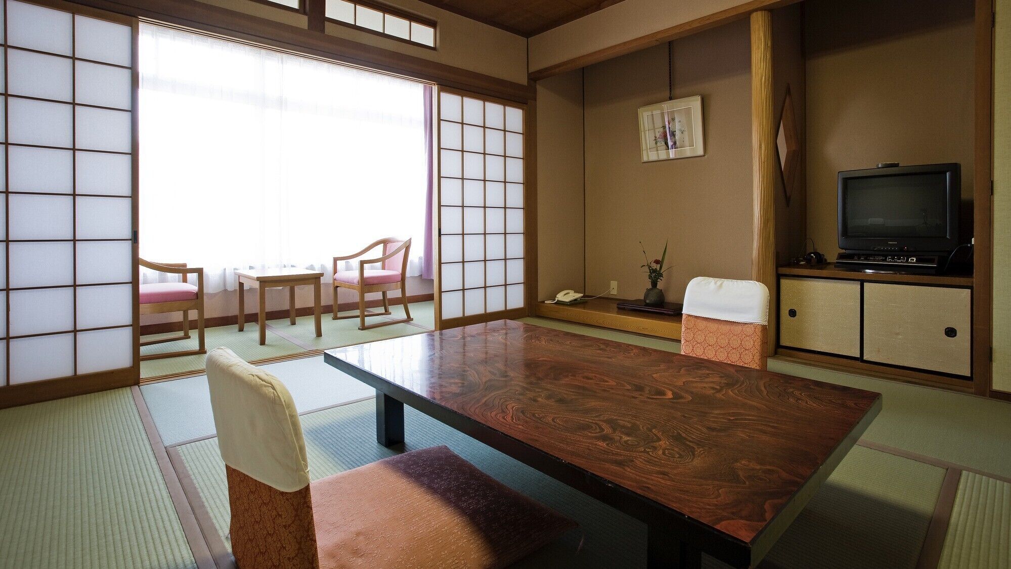 Una habitación japonesa tradicional con suelo de tatami, una mesa baja y puertas correderas.