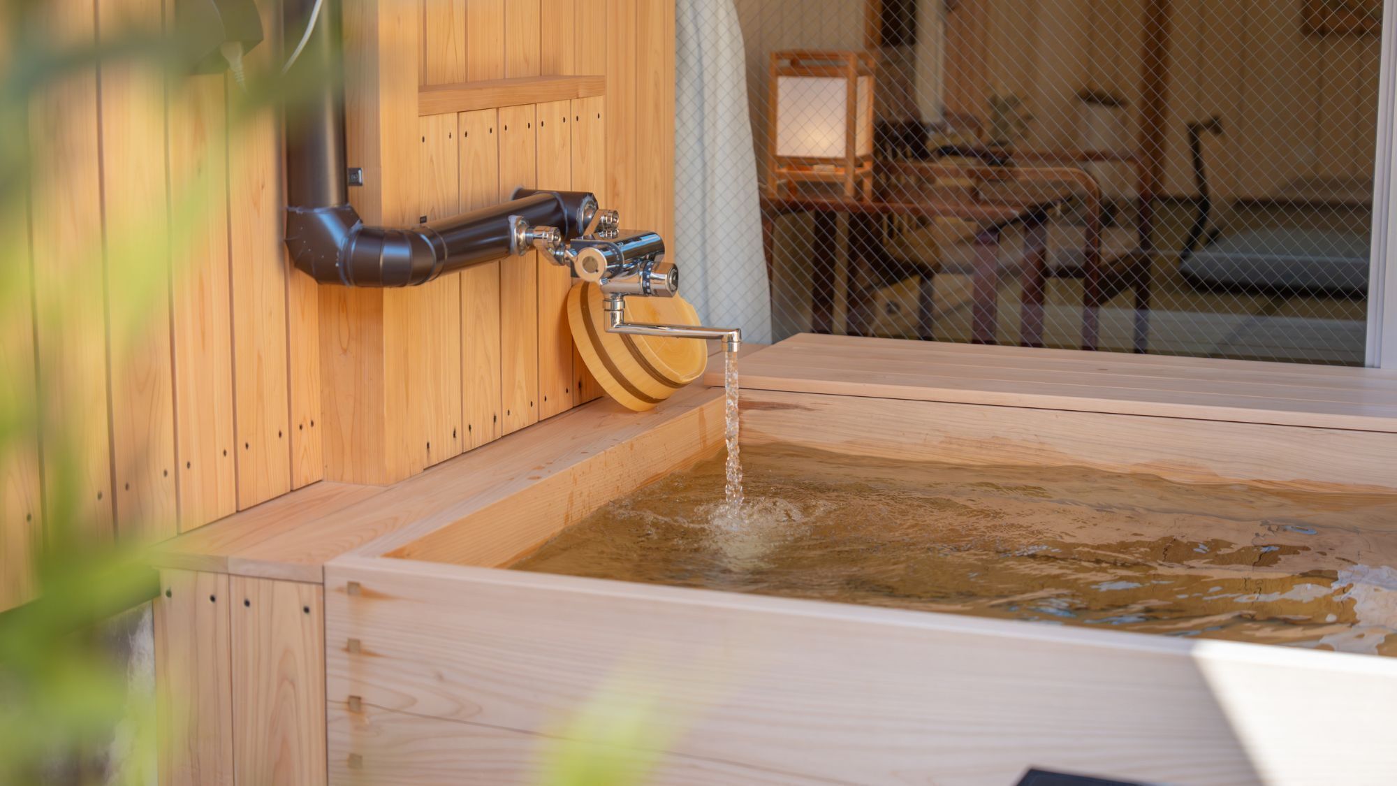 A wooden hot tub with a faucet and a wooden seat.
