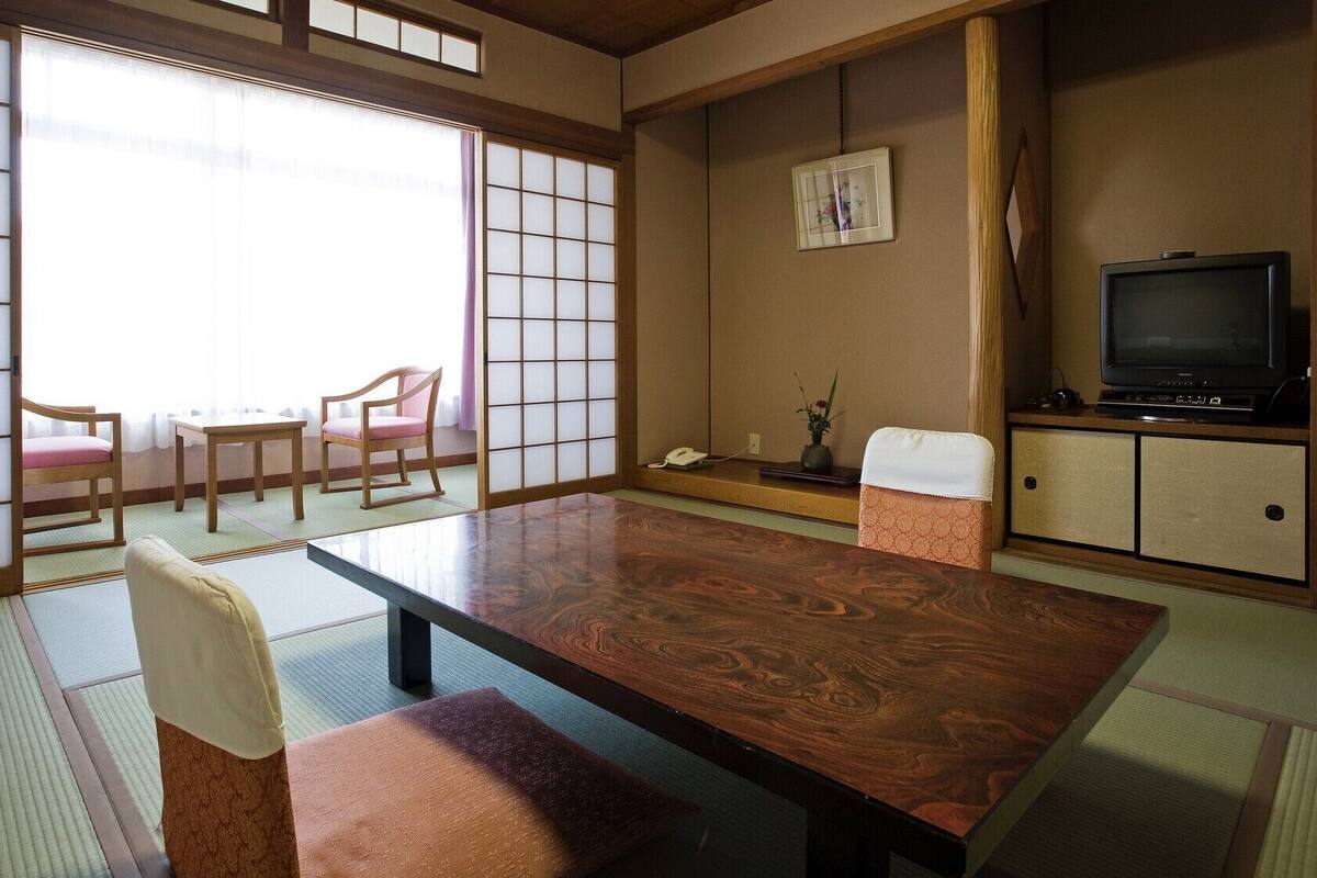 Um quarto japonês tradicional com tatames, uma mesa baixa e portas deslizantes.
