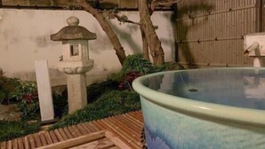 Un farol de piedra, una fuente de agua y una valla de bambú en un jardín.