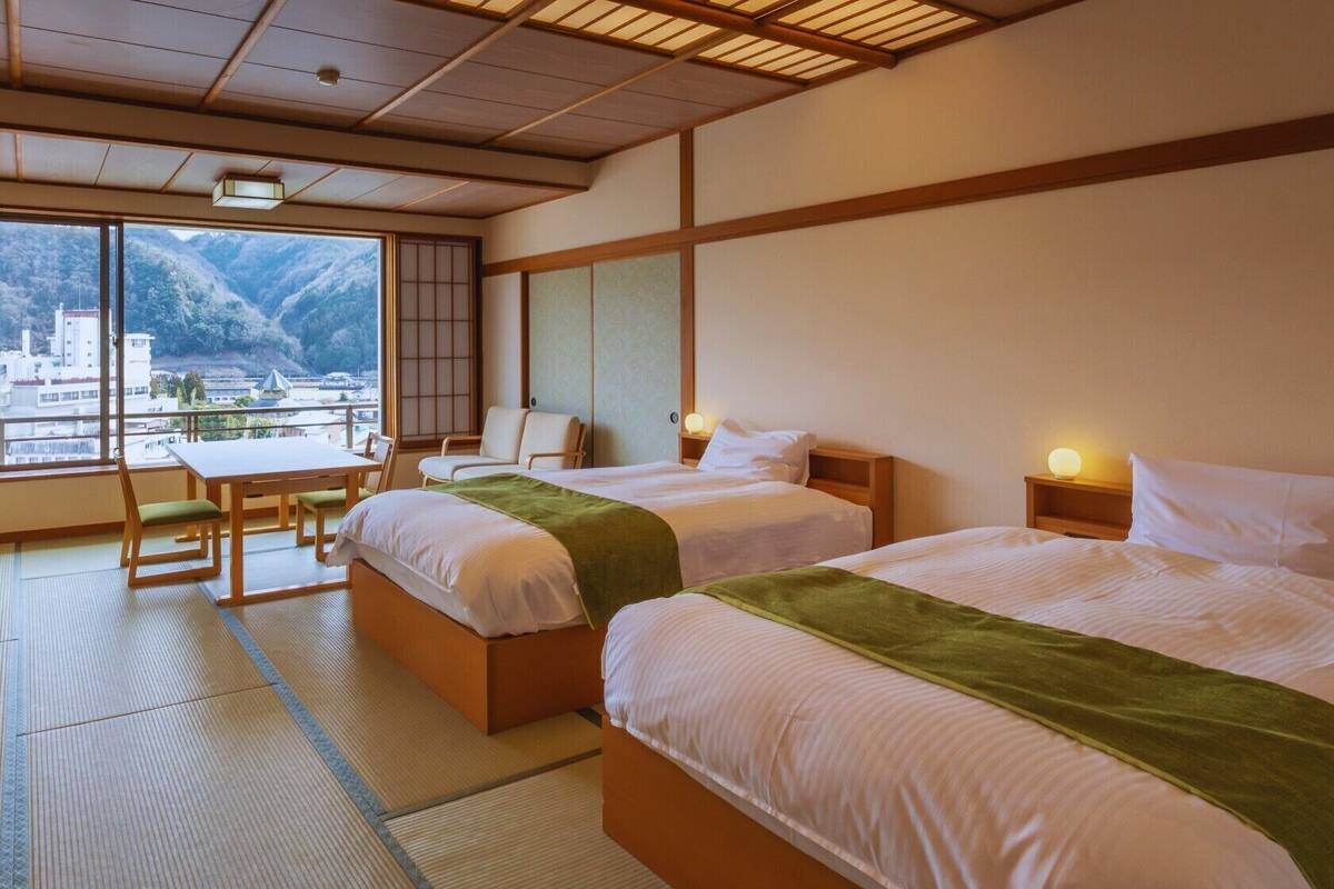 Quarto de hotel com duas camas, uma mesa de jantar e vista para montanhas.