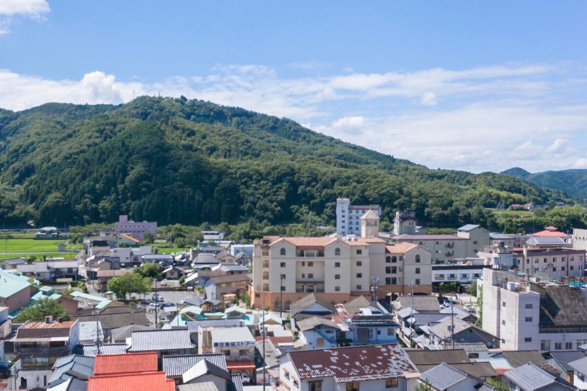 Uma cidade com edifícios tradicionais, uma igreja imponente e montanhas ao fundo.