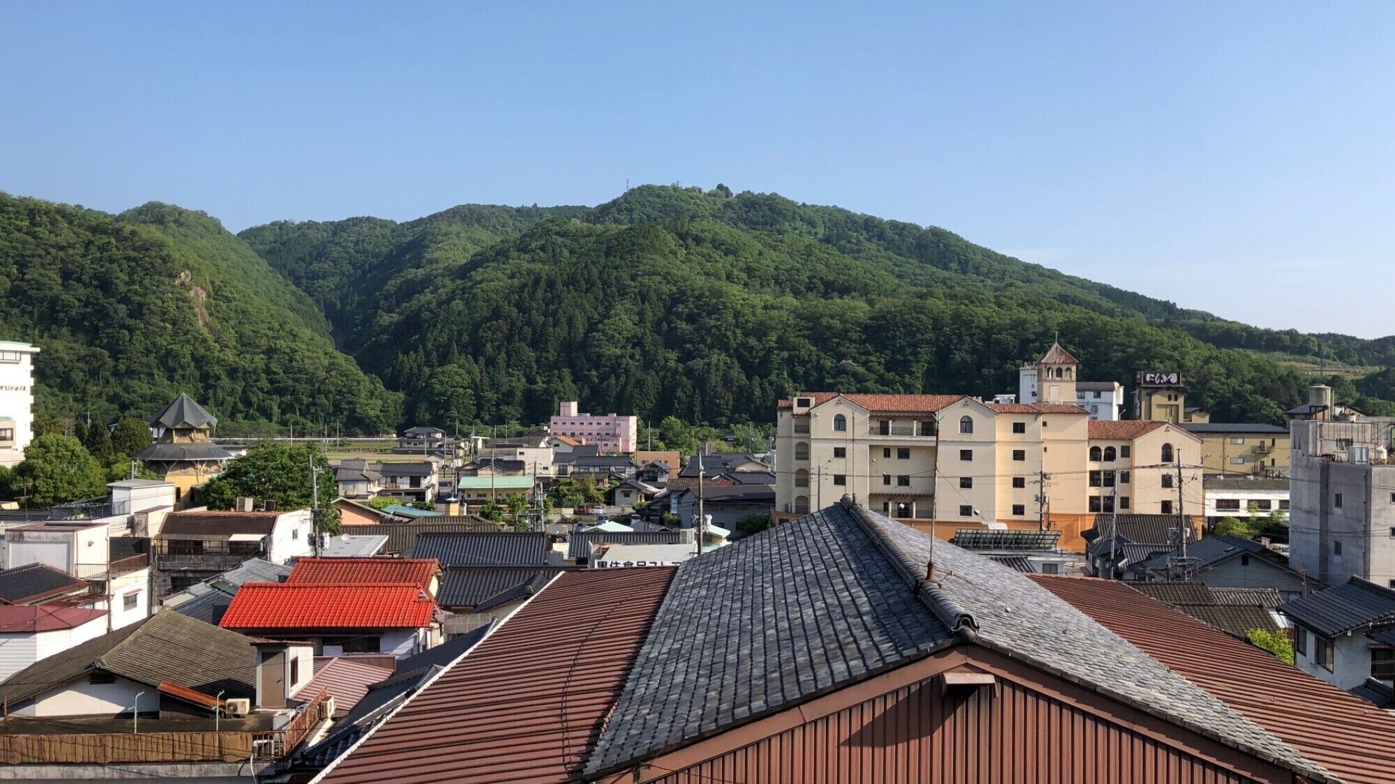 Un pueblo con edificios tradicionales y una colina al fondo.