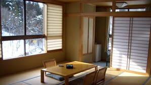 A tatami mat room with a low table and chairs, a sliding door, and a view of snow-covered trees. - Ryokan Tamanashi Onsen Ebisuya (Kaneyama)