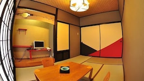 A traditional Japanese room with tatami flooring, a low table, a television, and sliding doors. - Ryokan Tamanashi Onsen Ebisuya (Kaneyama)
