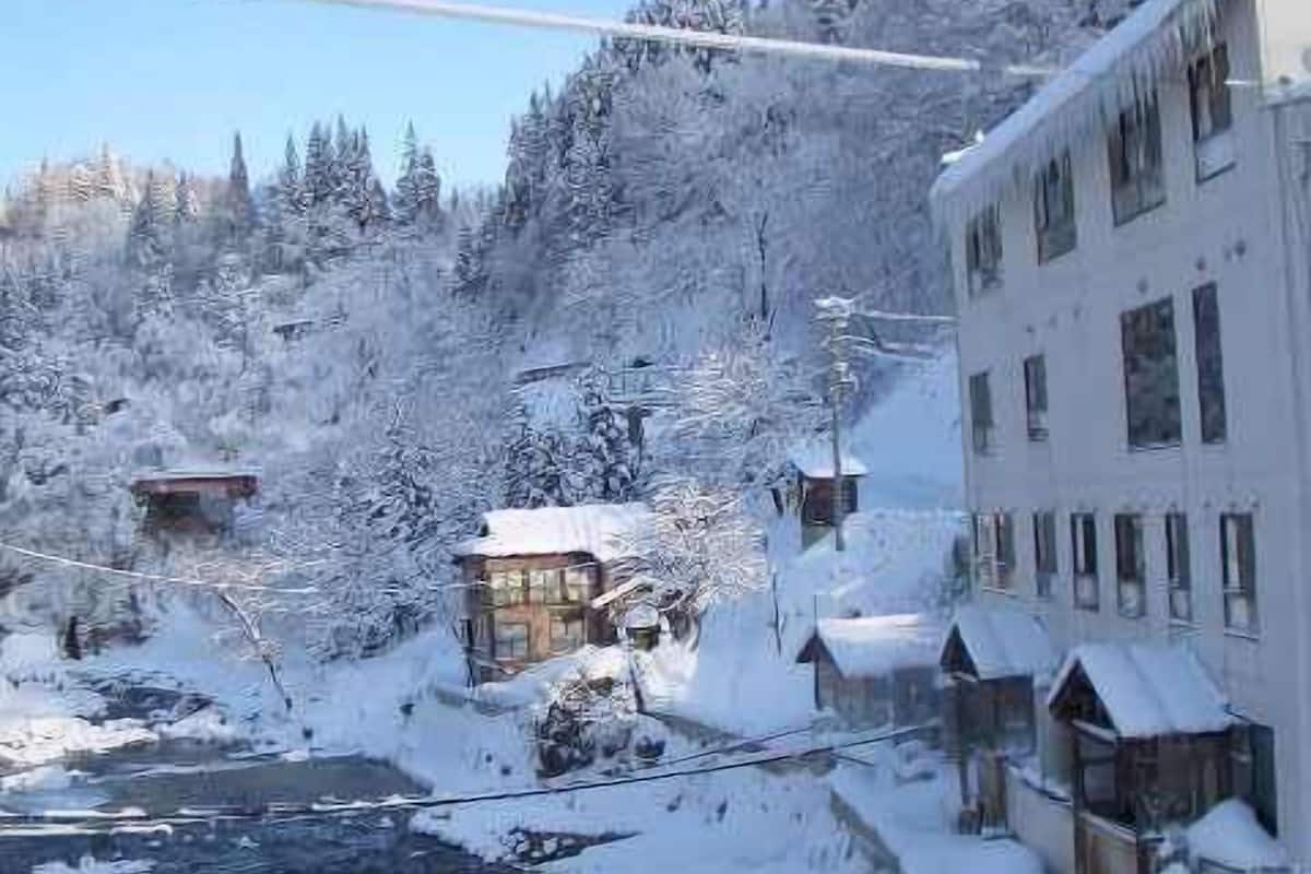 A snow-covered landscape with buildings, a river, and trees.
