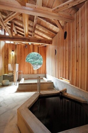 Un spa de madera con jacuzzi, una ventana con vistas al bosque y una sauna.