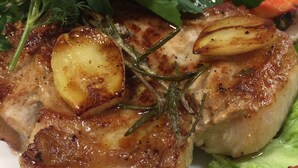 En tallerken mad med grillet kød, ristede kartofler og grøntsager.
