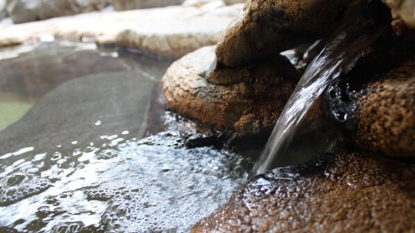 A natural water feature with a stream flowing over rocks into a pond. - Yakushido Spa (Oshu)