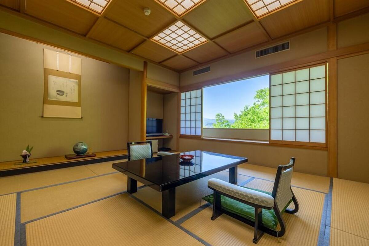 Una habitación japonesa tradicional con suelo de tatami, una mesa baja y puertas correderas.