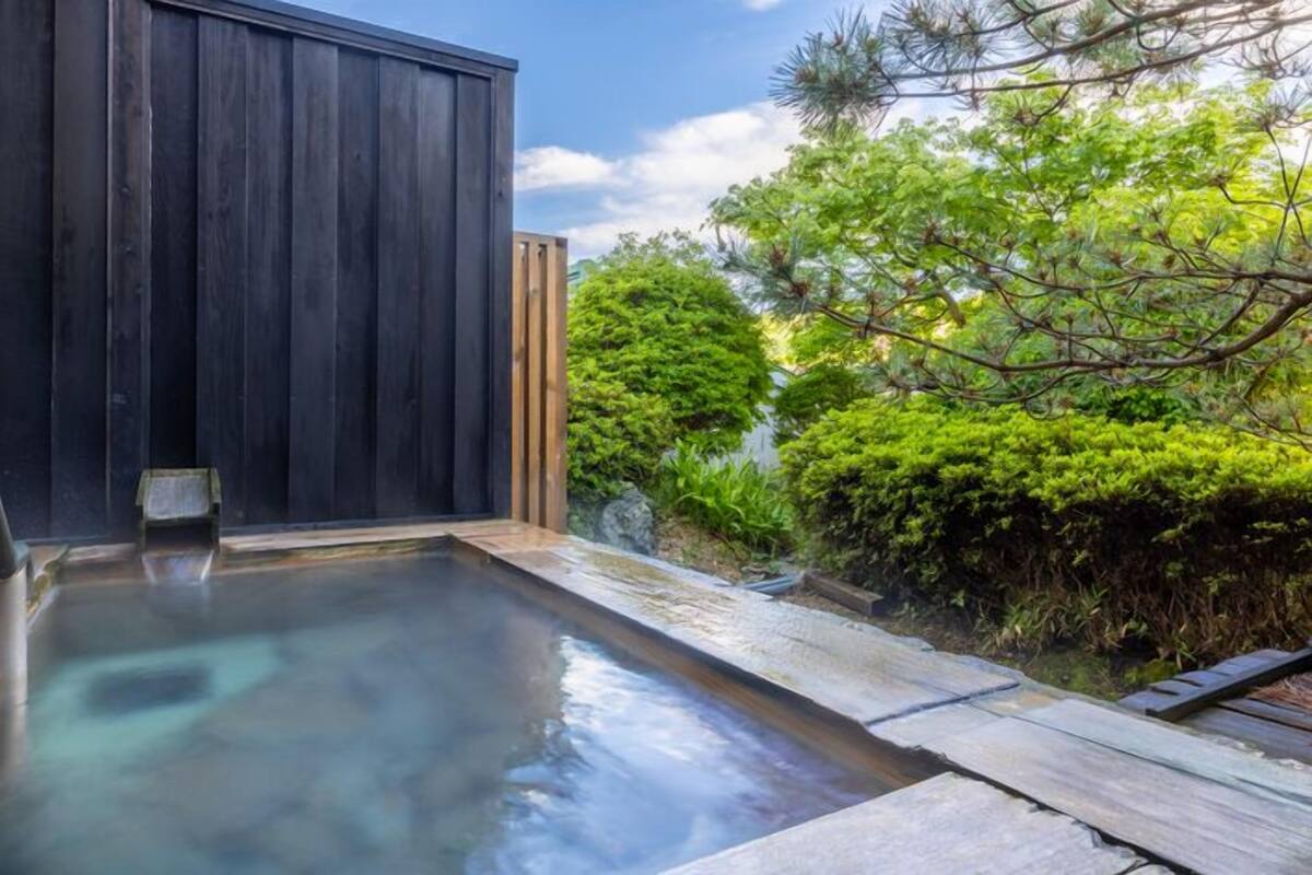 Un área de piscina moderna al aire libre con cubierta de madera y estructura de madera oscura.