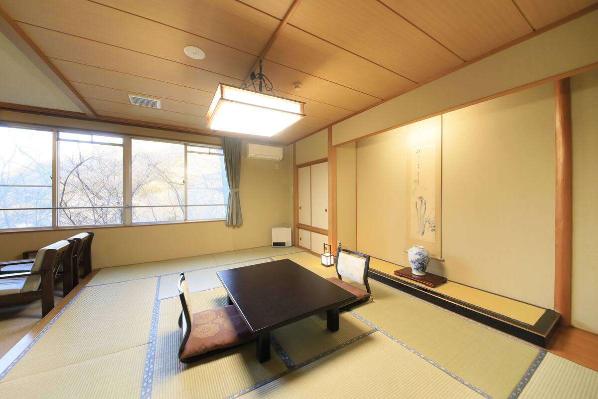 Una habitación japonesa tradicional con suelo de tatami, una mesa baja y puertas correderas.