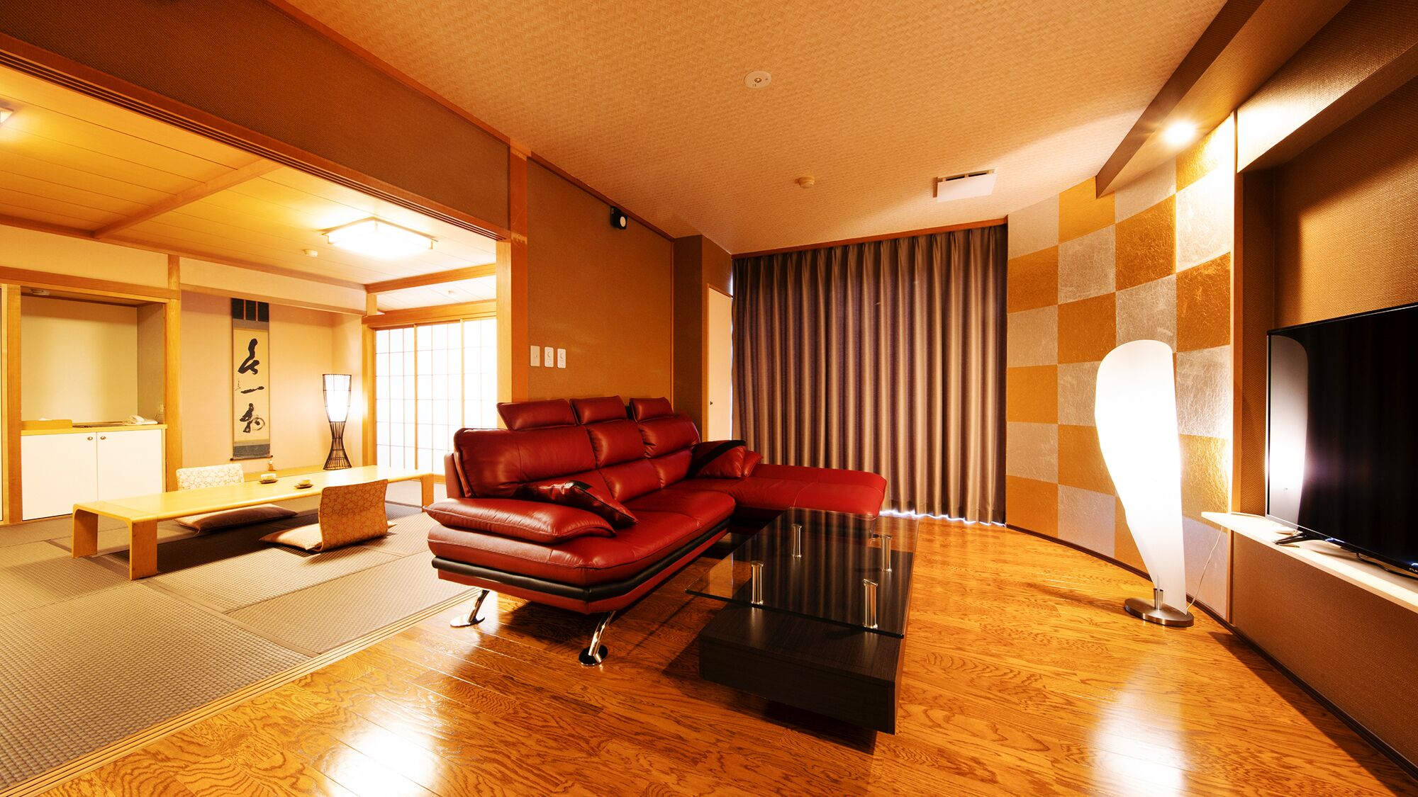 Un salon moderne avec un canapé en cuir, un téléviseur à écran plat et une esthétique d’inspiration japonaise traditionnelle.