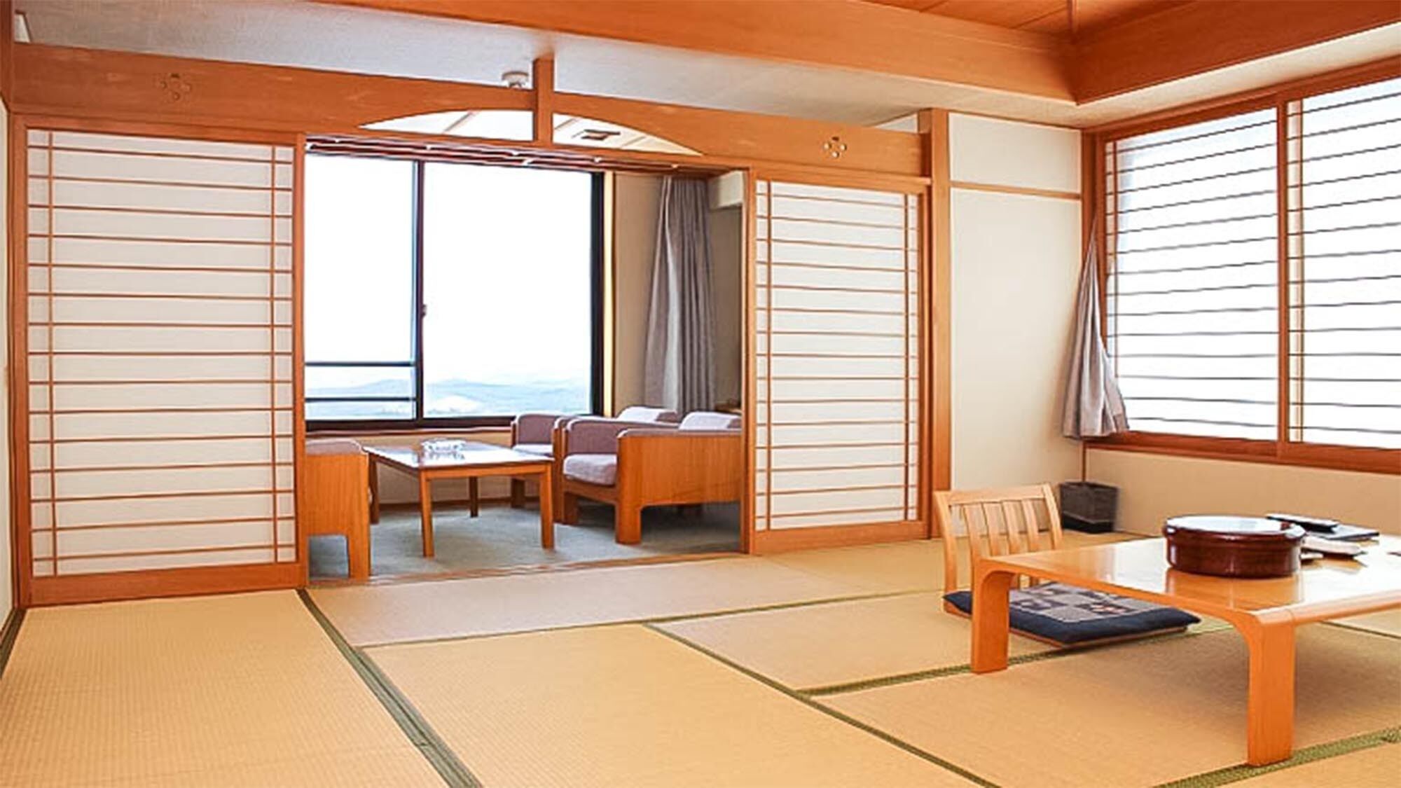 Een traditionele Japanse kamer met tatami vloeren, een lage tafel met kussens, een bank en schuifdeuren van shoji papier.