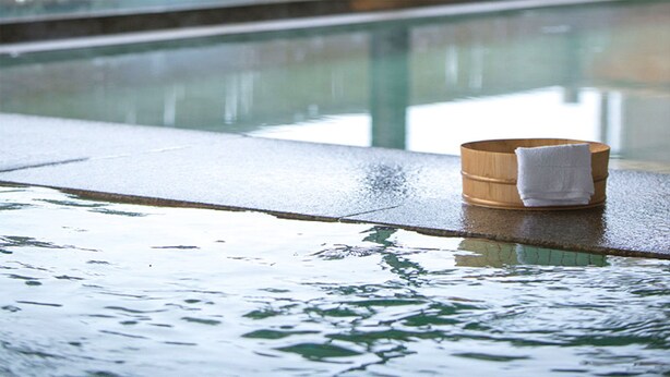 Un tapete de madera con una toalla junto a una piscina húmeda.