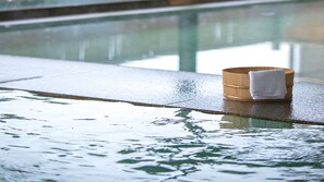 A wooden bath mat with a towel on a wet poolside.