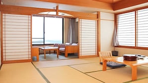 Una habitación tradicional japonesa con suelo de tatami, una mesa baja, sillas y puertas correderas.
