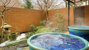 A hot tub area with a wooden fence and a covered structure. - Dochu Land Shin Onsen (Awa)