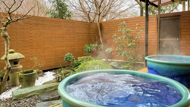 A hot tub area with a wooden fence and a covered structure. - Dochu Land Shin Onsen (Awa)
