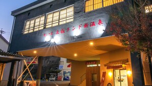 A building with a sign in Japanese, a covered entrance, and a vending machine outside. - Dochu Land Shin Onsen (Awa)