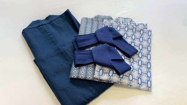 A neatly folded dark blue shirt and a patterned fabric with a bow tie. - Dochu Land Shin Onsen (Awa)