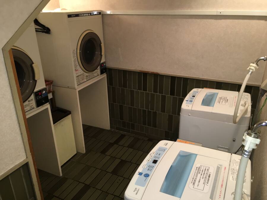 A laundry room with a front-loading washer, a stacked washer and dryer, and a water heater.